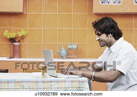 Stock Photo - Side profile of a young man listening to an MP3 player. Fotosearch