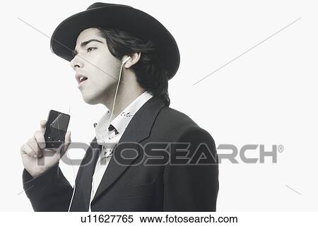 Stock Photography - Side profile of a young man listening to an MP3 player. Fotosearch