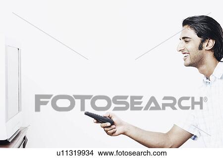 Picture - Side profile of a young man operating a remote control. Fotosearch