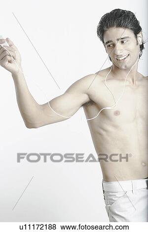 Stock Photo - Young man listening to music wearing headphones. Fotosearch