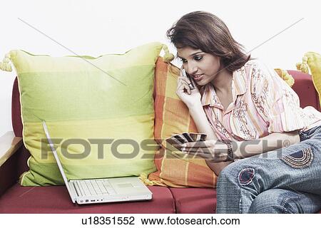 Stock Image - Close-up of a young woman on the telephone holding a credit card. Fotosearch