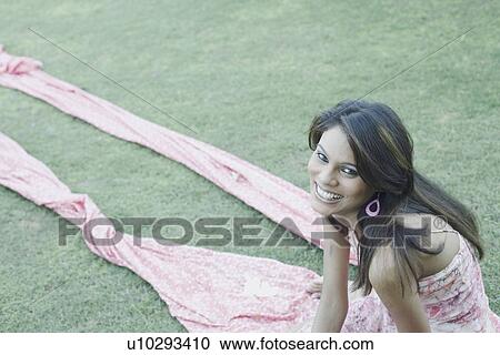 High angle view of a young woman sitting on a lawn View Large Photo Image Stock Image - High angle view of a young woman sitting on a lawn. Fotosearch