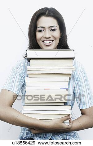 Stock Photo - Portrait of a young woman carrying a stack of books. Fotosearch