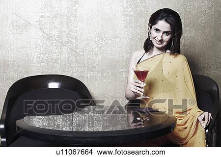 Portrait of a young woman holding a martini glass View Large Photo Image Picture - Portrait of a young woman holding a martini glass. Fotosearch