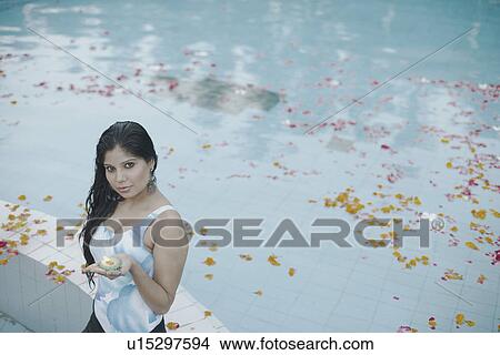Picture - Portrait of a young woman holding a candle standing in a swimming pool. Fotosearch