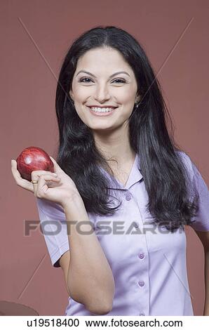 Portrait of a young woman holding an apple View Large Photo Image Stock Image - Portrait of a young woman holding an apple. Fotosearch