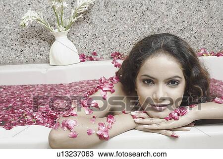 Stock Image - Portrait of a young woman in a bathtub covered with flower petals. Fotosearch