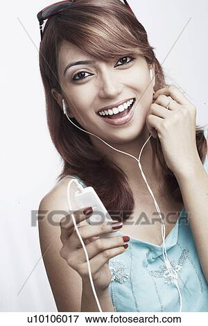 Stock Photo - Portrait of a young woman listening to an MP3 player. Fotosearch