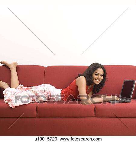 Portrait of a young woman lying in front of a laptop View Large Photo Image Stock Image - Portrait of a young woman lying in front of a laptop. Fotosearch