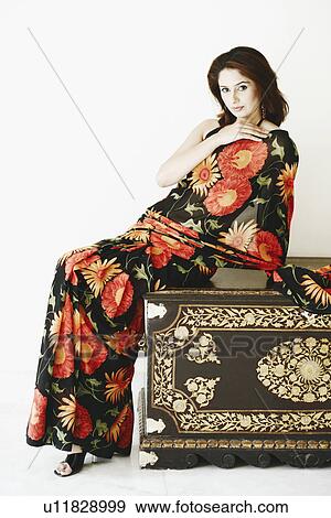 Stock Photo - Portrait of a young woman sitting on a wooden box. Fotosearch