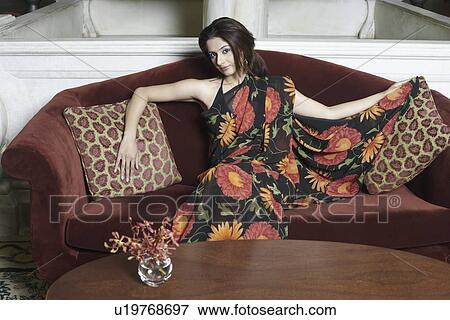 Stock Photo - Portrait of a young woman sitting on a couch. Fotosearch
