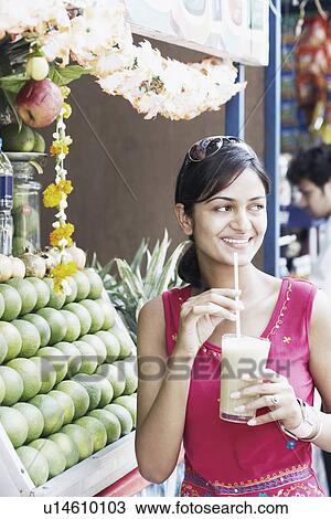 Young woman drinking juice with a straw View Large Photo Image Stock Image - Young woman drinking juice with a straw. Fotosearch