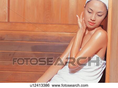 Stock Photograph - Asian woman sitting in sauna. Fotosearch