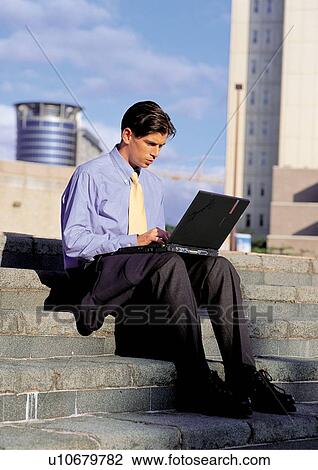 Stock Image - laptop, technology, building exterior, looking down, well dressed, business executive. Fotosearch