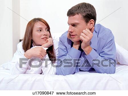 Stock Photo - bonding, relaxation, casual clothing, hands on chin, looking at each other, bed. Fotosearch