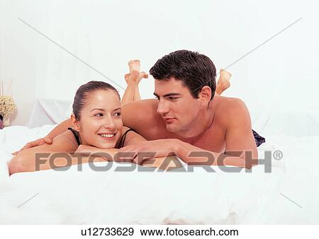 Stock Photo - indoor, casual clothing, romance, lying down, love, two people. Fotosearch