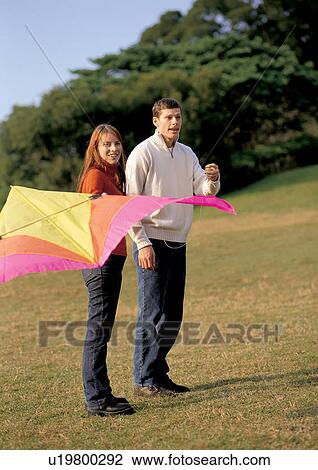 Stock Image - leisure activity, mid adult man, couples, affection, flying kite. Fotosearch