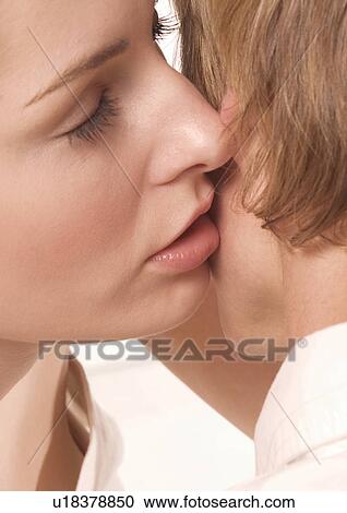 Stock Image - Close-up of a young woman kissing a young man's cheek. Fotosearch