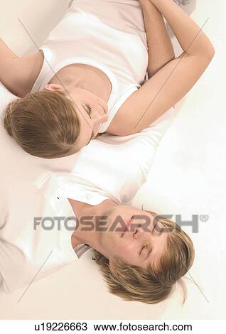 Stock Image - High angle view of a young couple sleeping. Fotosearch