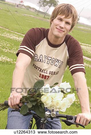 Portrait of a young man sitting on a cycle View Large Photo Image Stock Image - Portrait of a young man sitting on a cycle. Fotosearch