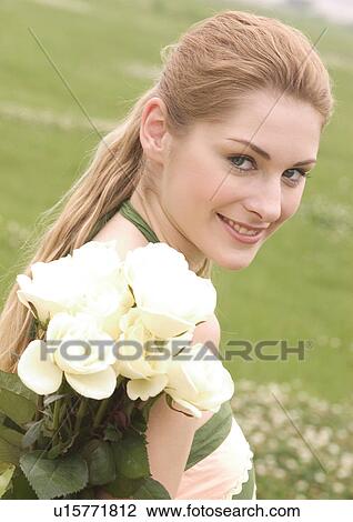 Portrait of a young woman holding a bouquet of white roses View Large Photo Image Stock Image - Portrait of a young woman holding a bouquet of white roses. Fotosearch