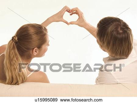 Stock Photo - Rear view of a young couple making a heart shape with their hands. Fotosearch