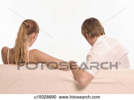 Stock Image - Rear view of a young couple sitting on a couch. Fotosearch