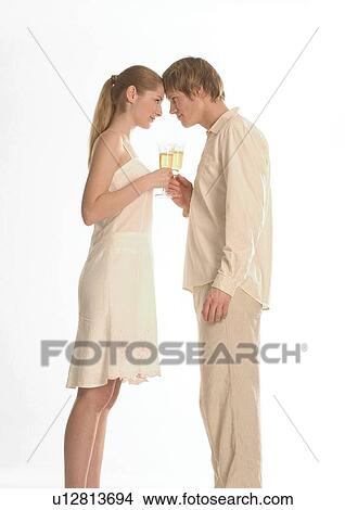 Picture - Side profile of a young couple holding champagne glasses. Fotosearch