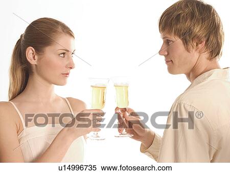 Stock Photography - Side profile of a young couple holding champagne glasses. Fotosearch