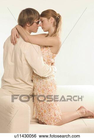 Side profile of a young couple kissing on a couch View Large Photo Image Stock Photograph - Side profile of a young couple kissing on a couch. Fotosearch
