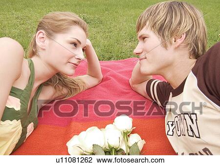 Side profile of a young couple lying on a picnic mat View Large Photo Image Stock Image - Side profile of a young couple lying on a picnic mat. Fotosearch
