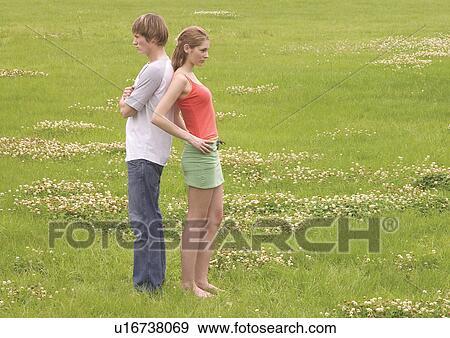 Stock Photo - Side profile of a young couple standing back to back. Fotosearch