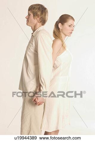 Side profile of a young couple standing back to back View Large Photo Image Stock Photo - Side profile of a young couple standing back to back. Fotosearch