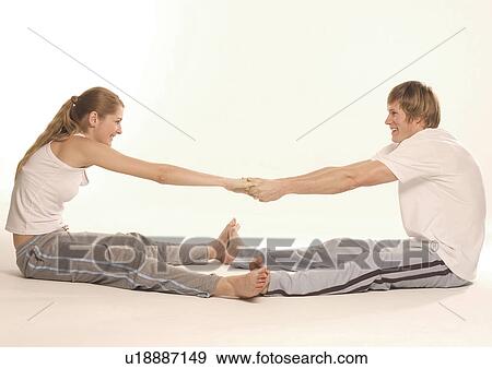 Stock Photo - Side profile of a young couple exercising on the floor. Fotosearch