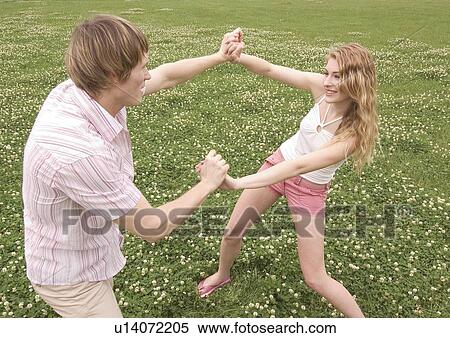 Side profile of a young couple playfully wrestling in a lawn View Large Photo Image Stock Photography - Side profile of a young couple playfully wrestling in a lawn. Fotosearch