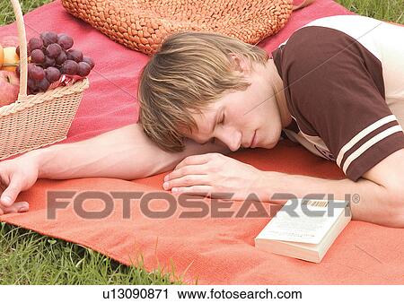 Stock Image - Side profile of a young man sleeping on a picnic mat. Fotosearch