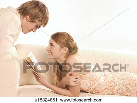Side profile of a young woman reading to a young man View Large Photo Image Stock Image - Side profile of a young woman reading to a young man. Fotosearch