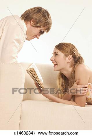 Stock Photo - Side profile of a young woman reading to a young man. Fotosearch