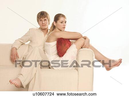 Young couple sitting on a couch View Large Photo Image Picture - Young couple sitting on a couch. Fotosearch