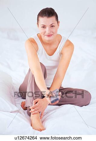 Picture - hand on foot, cushion, duvet, looking at camera, bedding, quilt. Fotosearch