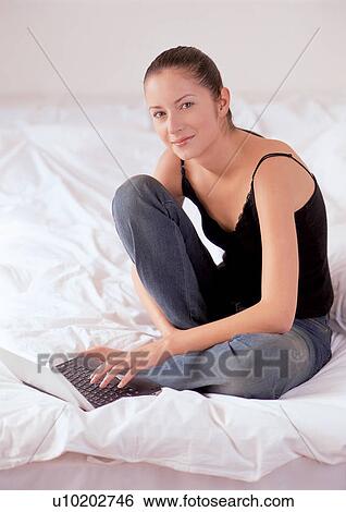 Stock Photograph - happy, bed sheet, bedding, happiness, looking at camera, brown hair, pillow. Fotosearch