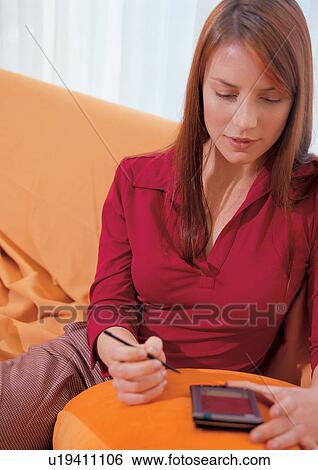 Stock Photograph - holding, young adult, pillow, casual clothing, digital diary, brown hair. Fotosearch