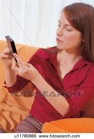 Stock Photograph - leisure new generation, indoor, youthful, viewing, young adult, hand held device. Fotosearch