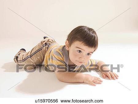 Close-up of a boy lying on his stomach View Large Photo Image Stock Photograph - Close-up of a boy lying on his stomach. Fotosearch