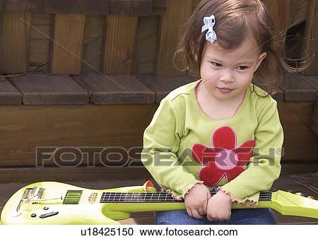 Stock Image - Close-up of a girl holding a guitar. Fotosearch