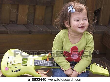 Close-up of a girl holding a guitar View Large Photo Image Stock Image - Close-up of a girl holding a guitar. Fotosearch