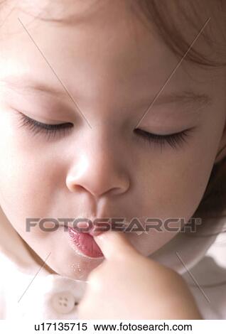 Stock Photography - Close-up of a girl with her finger in her mouth. Fotosearch