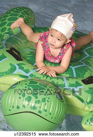 High angle view of a girl on a raft in a swimming pool View Large Photo Image Stock Photography - High angle view of a girl on a raft in a swimming pool. Fotosearch
