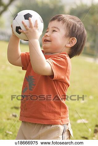 Stock Photography - Side profile of a boy holding a football. Fotosearch