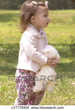 Picture - Side profile of a girl hugging a stuffed toy. Fotosearch